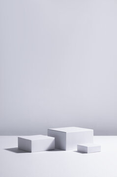 Fashion modern abstract showcase with set white square podiums in sunlight with shadow for cosmetics product display, vertical.