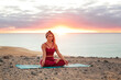 © merla - Woman practicing meditation on a cliff by the ocean at sunrise