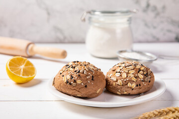 Poster - Closeup shot of freshly baked multigrain mixed cereal seed healthy bread buns on a white plate