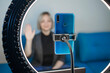 Video blogging. Business style woman talking to camera and recording video with smartphone and ring light lamp at home, working from home concept, social distant reality