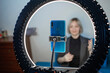 © Maria - Video blogging. Business style woman talking to camera and recording video with smartphone and ring light lamp at home, working from home concept, social distant reality