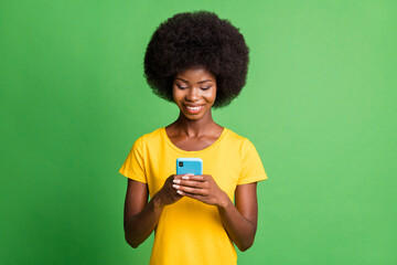 Photo of young happy cheerful good mood afro girl blogger addicted to smartphone isolated on green color background