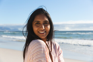 Wall Mural - Portrait of smiling mixed race woman on beach holiday looking to camera