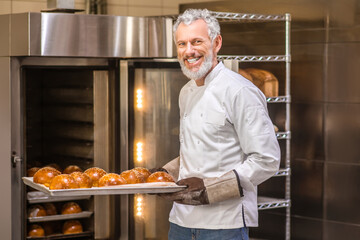 man in gloves with tray of freshly baked buns