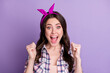 Photo portrait of ecstatic screaming girl with two raised fists isolated on vivid purple colored background