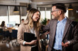 © JustLife - Colleagues in office. Businesswoman and businessman discussing work in office.
