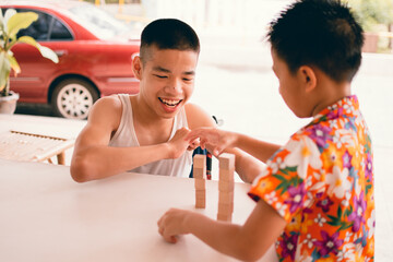 Wall Mural - Asian Special need child on wheelchair smile and interested in skills development toy wood block playing fun with friend,Lifestyle of education age for disabled children,Happy disability kid concept.