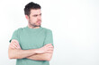 © Jihan - Displeased young handsome caucasian man wearing green t-shirt against white background with bad attitude, arms crossed looking sideways. Negative human emotion facial expression feelings.