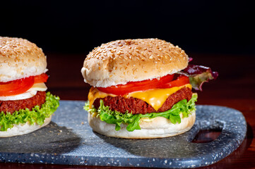 Wall Mural - Tasty vegetarian food, homemade cheeseburgers made from plant based soya meat with cheese, onion, green lettuce and tomatoes