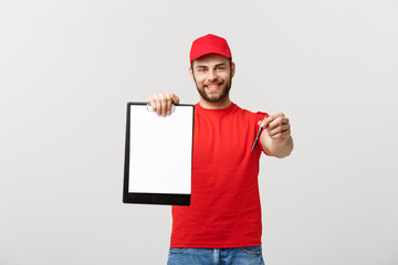 Wall Mural - Delivery Concept: Portrait Young caucasian Handsome delivery man or courier showing a confirmation document form to sign. Isolated on Grey studio Background. Copy Space.