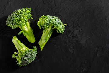 Wall Mural - Fresh raw broccoli (Brécol, brócolli, bróqui, broccoli brote, brassica oleracea) stalks with water drops on textured slate background. With copy space. Mediterranean diet food.