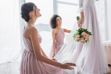 Poster - happy multicultural bridesmaids looking at bride holding wedding bouquet.