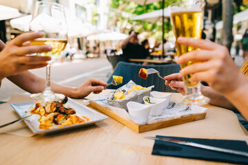 a glass of beer and wine on a table with utensils two girls have dinner together in a restaurant on the terrace in summer