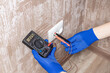 © Andrii - handyman electrician measuring wall outlet voltage at living room. outlet repair concept. test house wiring conceptual