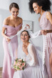 © LIGHTFIELD STUDIOS - happy multicultural women covering laughing bride with veil in bedroom.