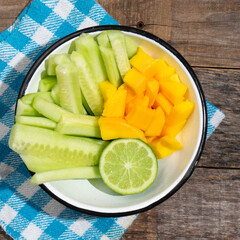 Wall Mural - Cucumber and mango salad on wooden background