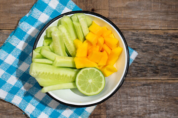 Wall Mural - Cucumber and mango salad on wooden background