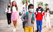 © JackF - Portrait of schoolboy in medical mask standing near school, kids on background