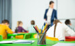 Closeup of multicolored pencils on school table on blurred background with teacher conducting lesson with children