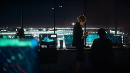 Wall Mural - Female and Male Air Traffic Controllers with Headsets Talk in Airport Tower at Night. Office Room Full of Desktop Computer Displays with Navigation Screens, Airplane Flight Radar Data for Controllers.