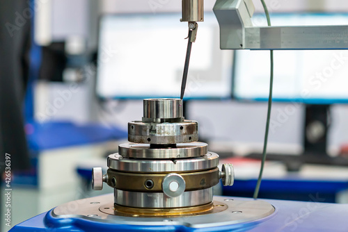 Obraz Dibond Machining cylindrical metal part set on work turntable on roundness cylindricity and straightness measuring tester machine and during inspection