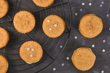 Wall Mural - Cream filled sandwich cookies with sprinkles on dark background