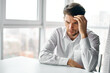 © SHOTPRIME STUDIO - puzzled man sitting at a table indoors and touching his head with his hand