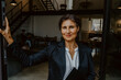 © Maskot - Portrait of businesswoman leaning at doorway in office