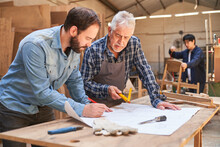 Senior Craftsman And Apprentice Look At Construction Plan