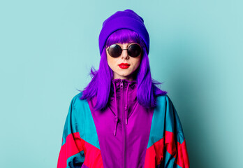 Wall Mural - Stylish white girl with purple hair, 80s tracksuit and sunglasses on blue background