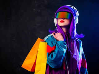 Stylish girl in cyber punk glasses and 80s tracksuit with shopping bags and headphones