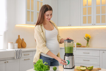 Sticker - Young pregnant woman preparing smoothie at table in kitchen. Healthy eating