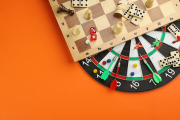 Wall Mural - Different types of board games and its' components on orange background, flat lay. Space for text