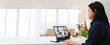 © weedezign - Video conference meeting from home.asian woman say hi to coworker on teleconference collaboration with laptop at home.banner space for display of content