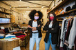 Portrait of two women owners of the dress shop at the entrance to welcome customers during the Coronavirus Covid-19 pandemic wearing protective face masks - Millennial initiate a start-up business