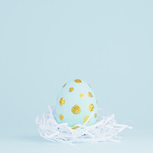 Festive Easter Background - Blue Easter Egg With Golden Glitter Dots In White Nest On Blue, Square.