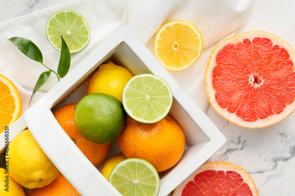 Basket with fresh citrus fruits on light background