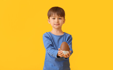 Poster - Cute little boy with chocolate Easter egg on color background