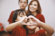 © Gatot - Closeup of two little daughters making heart shape with hands, with blurry photo of parent on the background. Love and Happy family concept