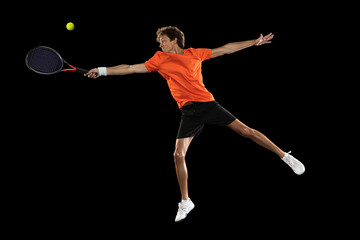 Wall Mural - Young Caucasian man, tennis player training isolated on black background.