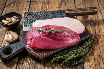 Fresh Raw Duck breast  fillet steaks on butcher board with meat cleaver. wooden background. Top View