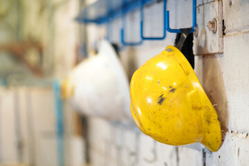 An used industrial safety hardhat or helmet, there are keep on wall hanging hook for good house keeping. Close-up and selective focus, Industrial equipment photo.