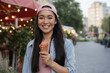 Beautiful smiling asian woman holding ice cream cone, looking at camera on the street, copy space. Food fair concept