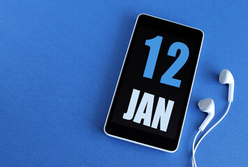 January 12. 12 st day of the month, calendar date. Smartphone and white headphones on a blue background. Place for your text. Winter month, day of the year concept.