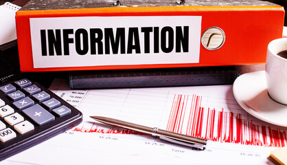 Fototapete - The red document folder says INFORMATION next to the coffee, calculator and pen.