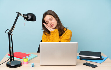 Student girl studying in her house isolated on blue background making sleep gesture in dorable expression