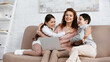 © LIGHTFIELD STUDIOS - Smiling mother hugging kids near laptop on couch.