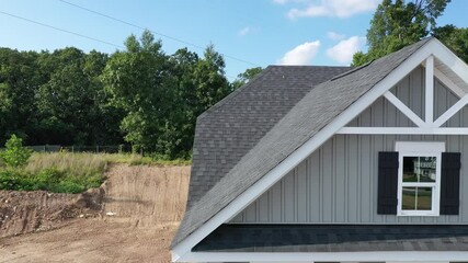 Wall Mural - Horizontal flight along a triangle shape decorative gable with colonial white soffit and fascia on a gray horizontal vinyl siding modern American estate home with cloudy blue sky