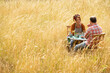 © Martin Barraud/Caia Image - Couple enjoying fruit at table in sunny summer field of tall grass