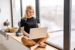© Angelov - Remote work at home, freelance during covid-19 quarantine. Smiling lady sitting and working on laptop in cozy living room interior, free space